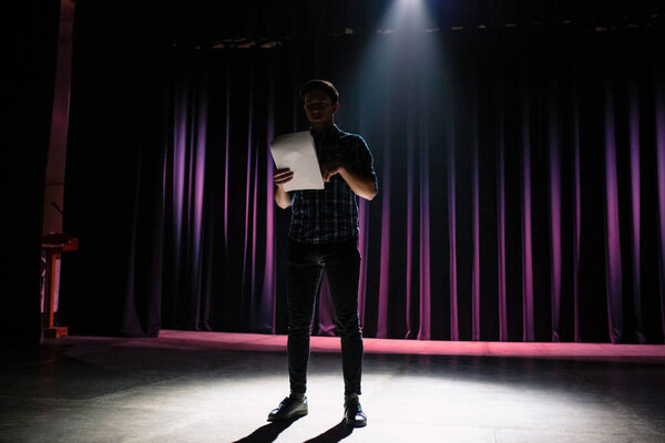 Medium shot of actors and actresses rehearsing a scene in a theater. Medium shot of an actor performing a monologue in a theater while holding his script