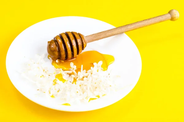 Plate with honey and spoon on yellow background — Stock Photo, Image