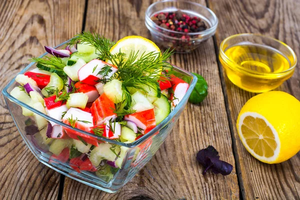 Vegetable salad with crab sticks in glass salad bowl on wooden table — Stock Photo, Image