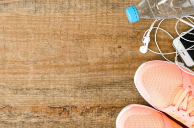 Spor ayakkabı, halter, su şişesi, ahşap arka plan üzerinde kulaklık ile Fitness kavramı