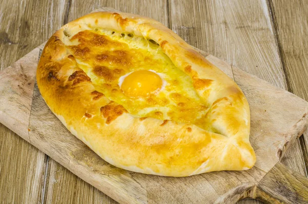 Peynir ve yumurta ahşap tahta üzerinde sıcak khachapuri — Stok fotoğraf