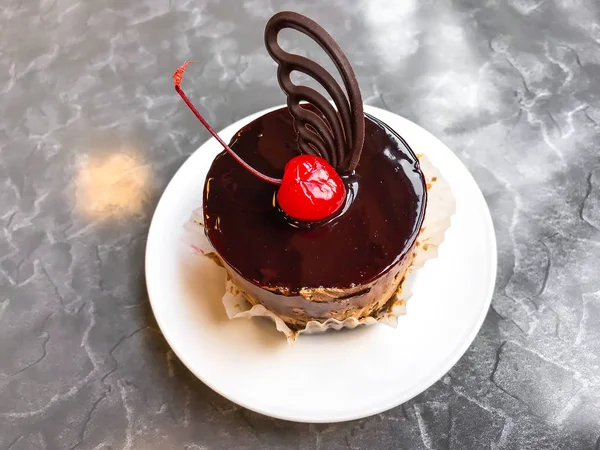 Round cake with chocolate icing and cherry. Studio Photo