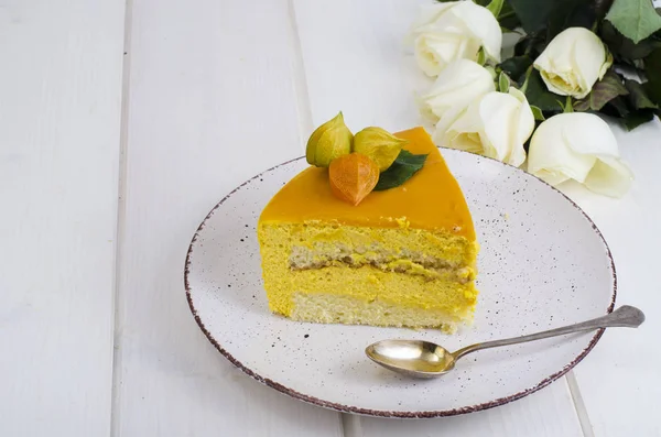 Piece of mango mousse cake on plate, white wooden table. Studio Phot