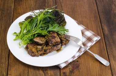 Dilim kızarmış karaciğer, yeşil salata yaprakları. Studio fotoğraf