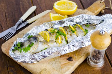 Fish carcass Dicentrarchus labrax with lemon, baked in foil with spices. Studio Photo clipart
