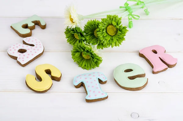 Kreative Grüße frohe Ostern. Schriftzug aus Keksen auf weißem Holzgrund. Pastellfarbenes Urlaubsbild. — Stockfoto