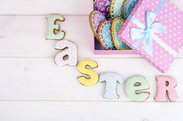Colorful easter egg in gift box, cookies biscuits letter Easter on wood background. — Stock Photo, Image