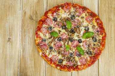 Ahşap yüzeyde jambon, mantar ve zeytin ile pizza.