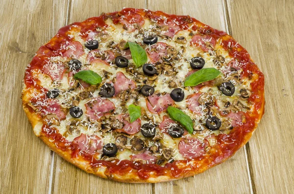 Ahşap yüzeyde jambon, mantar ve zeytin ile pizza.