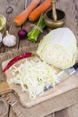 Dilimlenmiş Çin lahana, havuç, ahşap tahta üzerinde pişirme için baharatlar.