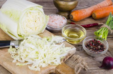 Dilimlenmiş Çin lahana, havuç, ahşap tahta üzerinde pişirme için baharatlar.