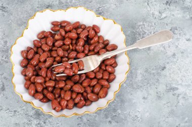 Gri arka planda beyaz tabakta kırmızı konserve fasulye