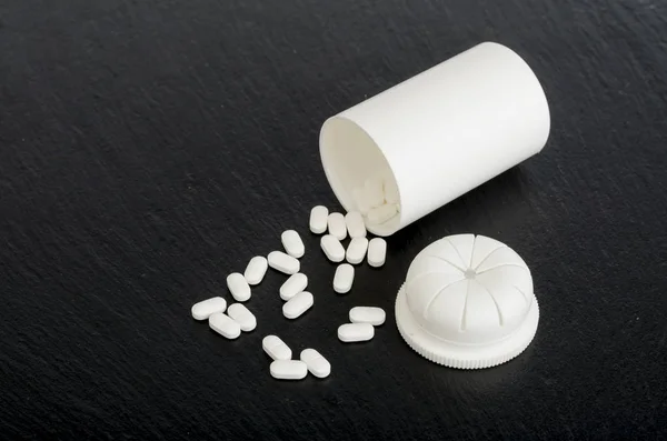 Білі медичні таблетки на чорному тлі. Фотографія — стокове фото