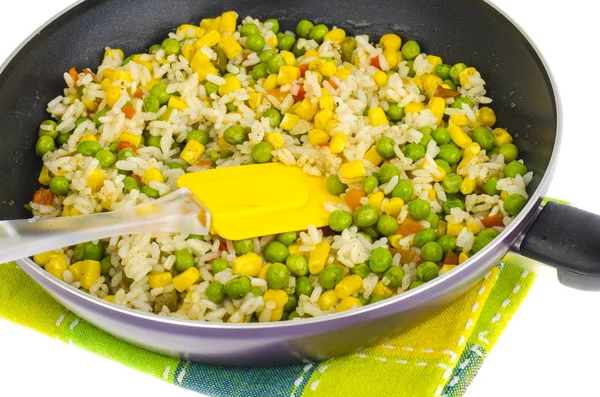 Stewed rice with corn, green peas in pan on white background.