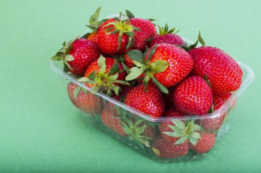 Plastik kapta taze tatlı kırmızı çilek. 