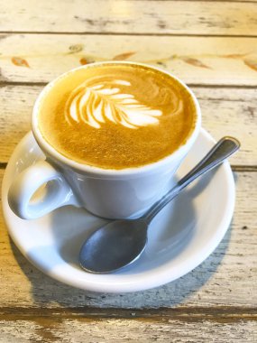 Eski ahşap masa üzerinde desen li kapuçino Fincan. 