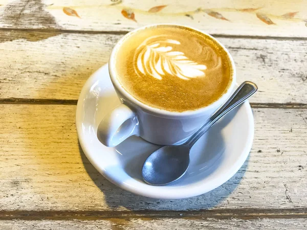 Tasse Cappuccino mit Muster auf altem Holztisch. — Stockfoto