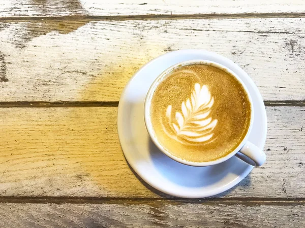 Xícara de cappuccino com padrão na mesa de madeira velha . — Fotografia de Stock