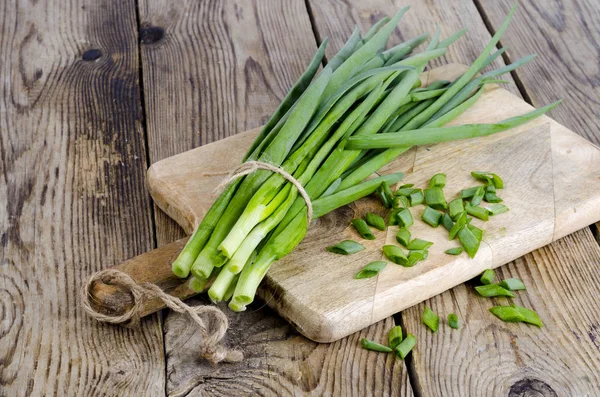 Knippe färsk grön lök på träbord. — Stockfoto