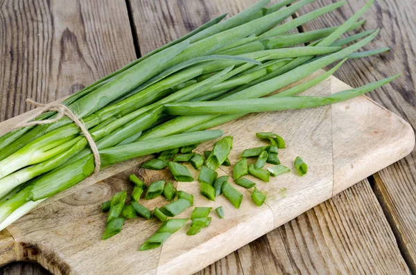 Knippe färsk grön lök på träbord. — Stockfoto