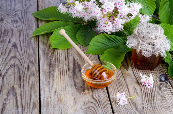 Duftender Kastanienhonig im Glas mit Blütenblüten. — Stockfoto