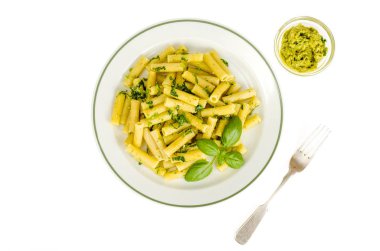 Beyaz tabakta ıspanak fesleğen pesto soslu Penne makarna.