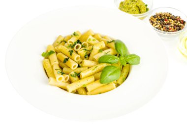 Beyaz tabakta ıspanak fesleğen pesto soslu Penne makarna.