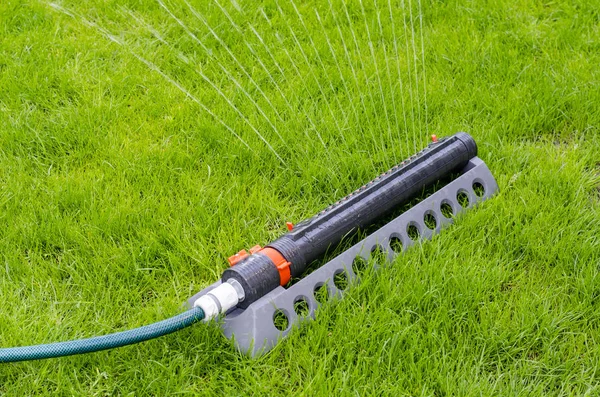 Irrigation system, sprinkler spaying water over green grass lawn — Stock Photo, Image