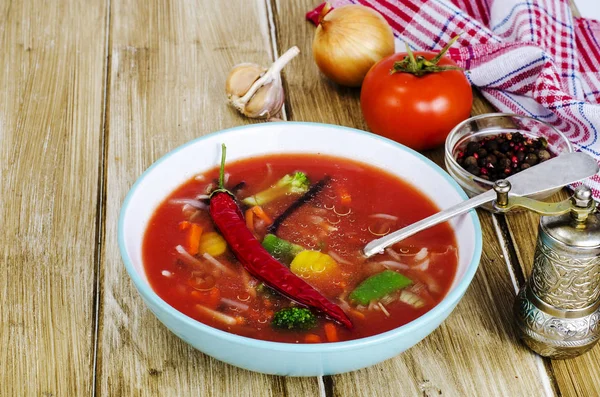 Pittige soep met tomaten op houten tafel — Stockfoto