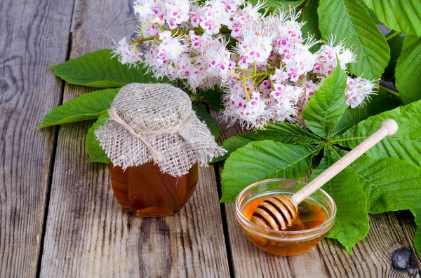 Duftender Kastanienhonig im Glas mit Blütenblüten. — Stockfoto