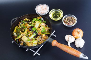 Siyah arka plan üzerinde tavada kızarmış patlıcan, kırmızı biber ve farklı sebzeler