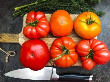 Ahşap mutfak tahtası üzerinde çok renkli taze domates.