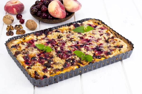 Домашний пирог с ягодами, фруктами и грецкими орехами в форме на светлом фоне . — стоковое фото