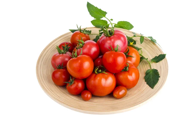 Prato de madeira com diferentes tomates maduros sobre fundo branco . — Fotografia de Stock