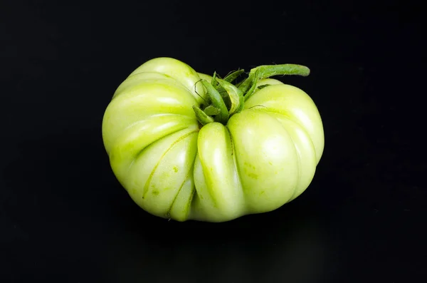 Zelené nezralé rajče na černém pozadí. Foto — Stock fotografie
