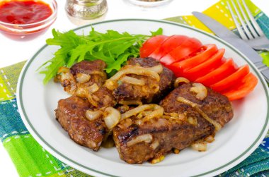 Soğanlı kızarmış ciğer parçaları, taze salata yaprakları. Stüdyo Fotoğrafı