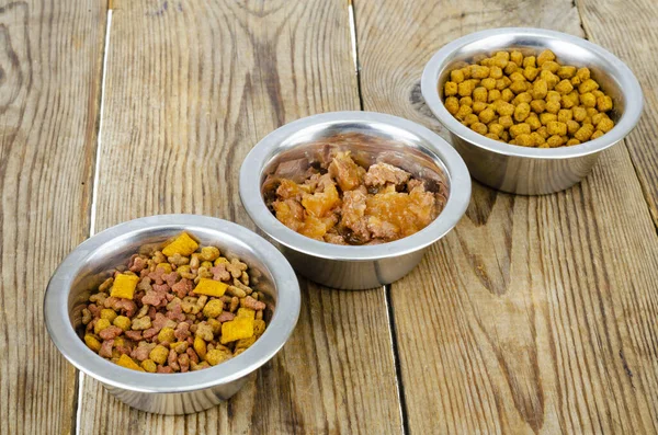 Metal bowls with different pet foods. Studio Photo