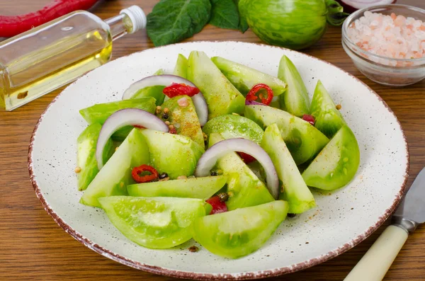 Appetizer of spicy pickled green tomatoes. Studio Photo