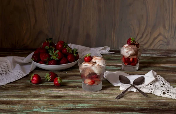 美味的冰淇淋与新鲜的草莓在杯子特写在一个木桌上 — 图库照片