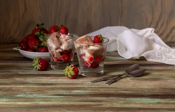 美味的冰淇淋与新鲜的草莓在杯子特写在一个木桌上 — 图库照片