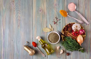 Baharatlar, zeytin yağ tabak ve kaşık ve mutfak otlar üzerinde yeşil, ahşap masa yakın çekim çeşitli.