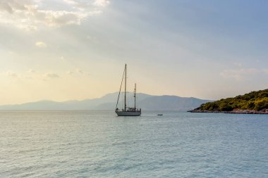 Bir sonbahar gecesi, güneşli günde kıyıya yakın açık denizde demirleyen Yelkenli Yat beyaz.