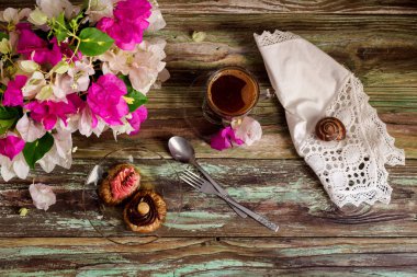 Hala hayat iki küçük kek bir tabak, bir buket çiçek ve bir fincan kahve yakın çekim ahşap zemin (Yunan mutfağı üzerine şurubu ile 