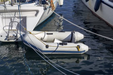 Güneşli bir gün yakın bir iskelede küçük, şişme beyaz tekne.