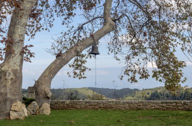 Kilise bell sonbahar günü (Yunanistan, Peloponnese büyük bir çınar bulutlu, dağlardaki bir arka plan üzerinde asılı)