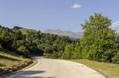 Kırsal bir dar yol ve dağlar görünümünü güneşli, bir yaz gününde (bölge Tzoumerka, Epirus, Yunanistan).