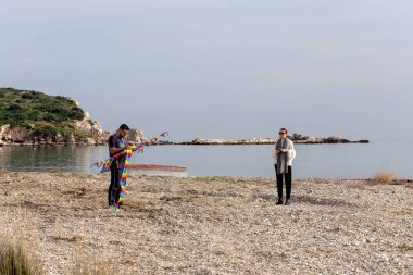 Genç adam ve kız bir bahar gününde bir uçurtma sahilde açmaya hazırlanıyor