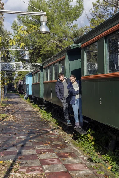在一个阳光明媚的冬日里 一个年轻美丽的女人和一个男人站在一辆旧火车的跑步板上 — 图库照片