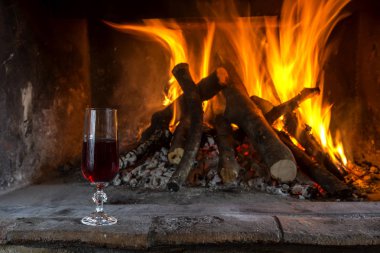 Kış sezonu yanan şömine. Yakacak odun yanan şömine ve bir bardak şarap yakın çekim.