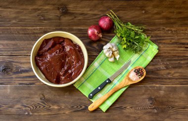 Yemek hazırlama. Ham sığır eti karaciğer kase ve ahşap masa yakın çekim sebze